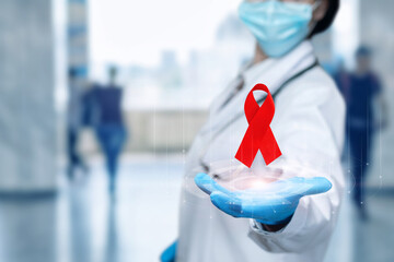 Doctor shows a red ribbon as a symbol of the fight against AIDS and cancer.