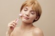 © Tatiana - a beautiful woman in a towel with clean skin, a sweet smile and brown hair pinned back hair on a beige background is standing with a massage roller in her hand.Horizontal studio shot.