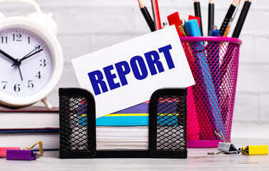 Fototapete - The office desk has diaries, an alarm clock, stationery, and a white card with the text REPORT. Business concept.