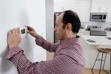 Man Installing And Setting Digital Thermostat At Home