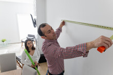 Father And Daughter Measuring Wall With Tape Measure