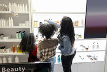 Mother And Daughters Shopping For Hair Care Products In Hair Salon