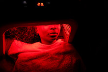 Close Up Young Woman Receiving Red Light Therapy In Dark Beauty Salon