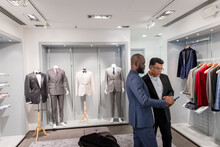 Tailor And Customer With Smart Phone In Menswear Shop