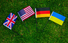 Close Up Great Britain, USA, Gemany And Ukraine Flags On Green Grass. National Symbol Of The Country