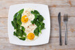 Plate with scrambled eggs and spinach on a wooden background