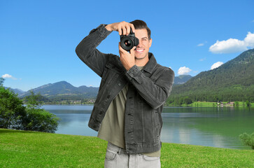 Sticker - Photographer holding professional camera and beautiful landscape with mountains and river on background