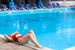 © Pixel-Shot - Pretty young woman lying near swimming pool