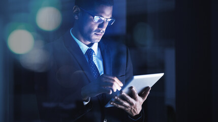 Leinwandbilder - Businessman working overtime on a digital tablet with glasses in a corporate modern office. Corporation manager reading company documents, data and statistics on an internet website with technology.