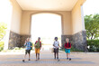 Full length of smiling multiracial elementary schoolboys with backpack entering school