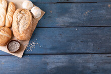 Directly Above Shot Of Various Breads With Seeds On Brown Wax Paper At Table