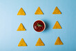 Overhead view of red sauce with rosemary amidst nacho chips arranged on blue background