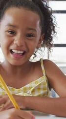 Wall Mural - video of happy biracial girl sitting at school desk and learning