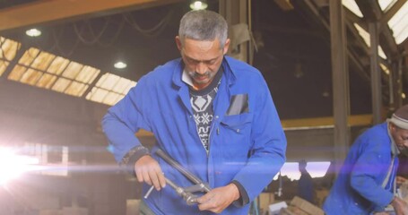 Poster - Animation of glowing light over biracial male mechanic in workshop
