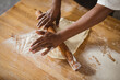 © Wavebreak Media - High angle view of cropped hands of african american mid adult male baker rolling dough at table