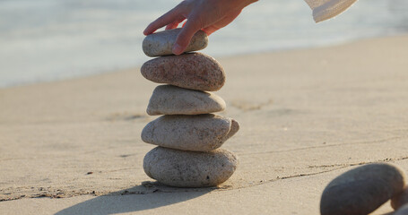 Canvas Print - Woman build zen stone tower with pebble stone