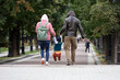 Young couple with kid boy walking on a street holding his hands, family leisure in autumn city