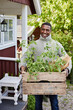 © Johnér - Smiling man holding crate with tomato plants