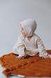 © Ananass - Cute studio portrait of a little newborn girl posing for a photo on a light background. A baby who has already learned to crawl and sit