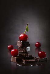 Wall Mural - Pieces of dark chocolate and fresh cherry on a dark background. Copy space