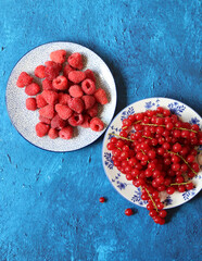 Poster - Red currant and raspberry on ceramic plates. Natural vitamins and anti oxidants. Blue textured background with copy space. 