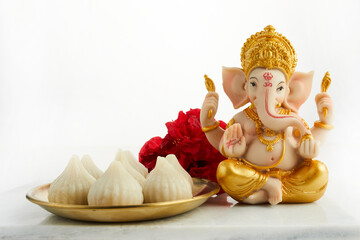 idol of lord ganesha with modak sweet dish and flower. ganesh chaturthi