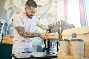 Cheerful young man working at cafe and sorting out food deliveries