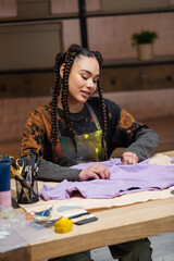 Wall Mural - Cheerful african american designer holding cloth in workshop.