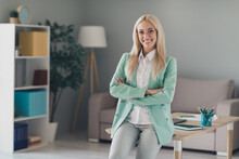 Photo Of Positive Good Mood Lady Wear Turquoise Jacket Sitting Table Smiling Arms Crossed Indoors Workstation Workshop
