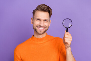 Wall Mural - Photo of cheerful positive guy wear orange sweater rising enlarge magnifier isolated violet color background