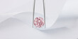 Pink Diamond in Tweezers on White Silk Background