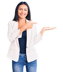 Sticker - Young beautiful latin girl wearing business clothes amazed and smiling to the camera while presenting with hand and pointing with finger.