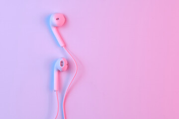 Wall Mural - Wired white earphones isolated on white background close-up in pink neon light