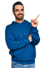 Wall Mural - Young hispanic man wearing casual clothes smiling happy pointing with hand and finger to the side