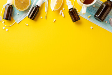 Wall Mural - Illness concept. Top view photo of medicines bottles pills capsules thermometer face masks cup of tea and cut lemon on isolated yellow background with empty space