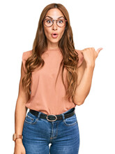 Young Hispanic Woman Wearing Casual Clothes And Glasses Surprised Pointing With Hand Finger To The Side, Open Mouth Amazed Expression.