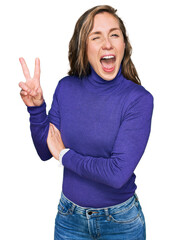 Sticker - Young blonde woman wearing casual clothes smiling with happy face winking at the camera doing victory sign. number two.