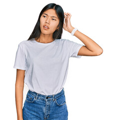 Sticker - Beautiful young asian woman wearing casual white t shirt confuse and wondering about question. uncertain with doubt, thinking with hand on head. pensive concept.