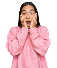 Wall Mural - Young asian woman wearing casual winter sweater afraid and shocked, surprise and amazed expression with hands on face