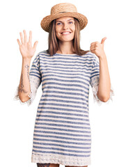 Wall Mural - Beautiful caucasian woman wearing summer hat showing and pointing up with fingers number six while smiling confident and happy.