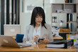 © SOMKID - Asian businesswoman working  with calculator and laptop computer at office workplace. business planning, investment and marketing on table in office.