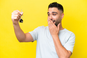 Young Arab man holding home keys isolated on yellow background with surprise and shocked facial expression