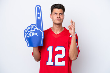 Wall Mural - Young caucasian sports fan man isolated on white background with fingers crossing and wishing the best