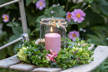 Wall Mural - Arrangement mit Blumenkranz mit Hortensien-Blüten und Buchs-Zweigen und Kerze im Glas