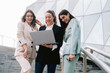 © ADDICTIVE STOCK - Group of businesswomen browsing laptop in downtown