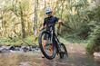 © ADDICTIVE STOCK - Cyclist walking with bicycle in shallow river in forest