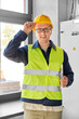 © Syda Productions - construction business and building concept - happy smiling male electrician or worker in helmet and safety west with papers on clipboard and pencil at electric board