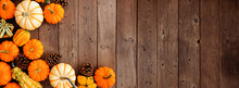 Autumn Corner Border Of Pumpkins, Gourds And Pine Cones. Top Down View On A Rustic Dark Wood Banner Background With Copy Space.