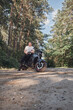 © perfectlab - Young male biker travels on a motorcycle alone, stopped and smoking on the side of a forest road