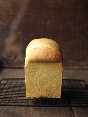 Wall Mural - fluffy loaf of bread on baking rack with wooden background